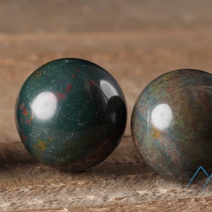 Natural Bloodstone crystal sphere, with wooden stand. This semi-precious, crystal ball is green with red hematite inclusions. Each crystal sphere is beautifully handcrafted, ethically sourced and comes with a wooden stand. This Listing has variations