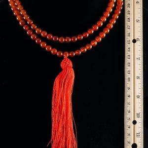 These red orange Carnelian necklaces have 108 sphere beads with a red tassel.  
Crystals are nature-made therefore each one is unique in appearance.