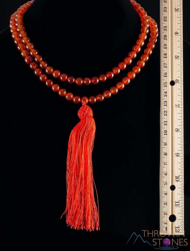 These red orange Carnelian necklaces have 108 sphere beads with a red tassel.  
Crystals are nature-made therefore each one is unique in appearance.