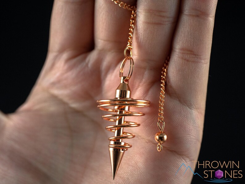 These copper pendulums are wire spirals with a pointed tip, with a copper chain and bead.