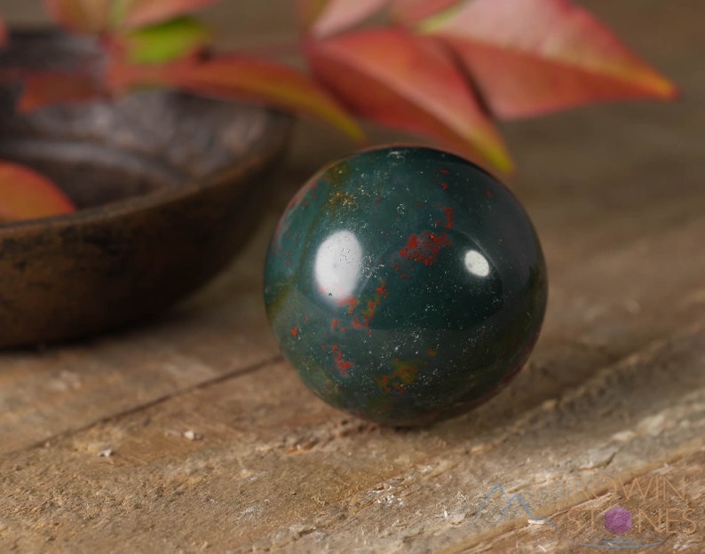 Natural Bloodstone crystal sphere, with wooden stand. This semi-precious, crystal ball is green with red hematite inclusions. Each crystal sphere is beautifully handcrafted, ethically sourced and comes with a wooden stand. This Listing has variations