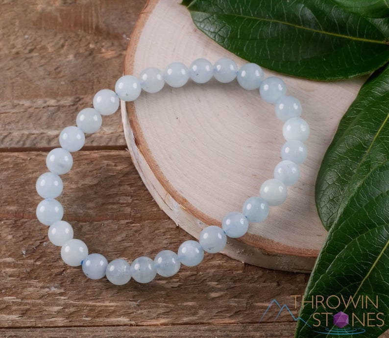 Handcrafted Aquamarine round beaded bracelet. These polished, blue beads are drilled and strung on elastic cord. Each crystal bracelet is unique in shape, color, and pattern and has a wrist circumference of about 6 to 7 inches. Listing has variations