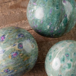 Peut inclure: Trois sphères de marbre vert, blanc et rose avec un motif moucheté. Les sphères sont lisses et polies.