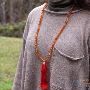 These red orange Carnelian necklaces have 108 sphere beads with a red tassel.  
Crystals are nature-made therefore each one is unique in appearance.