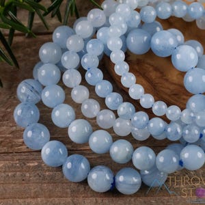 Handcrafted Aquamarine round beaded bracelet. These polished, blue beads are drilled and strung on elastic cord. Each crystal bracelet is unique in shape, color, and pattern and has a wrist circumference of about 6 to 7 inches. Listing has variations