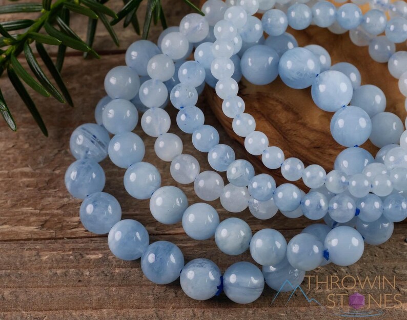 Handcrafted Aquamarine round beaded bracelet. These polished, blue beads are drilled and strung on elastic cord. Each crystal bracelet is unique in shape, color, and pattern and has a wrist circumference of about 6 to 7 inches. Listing has variations