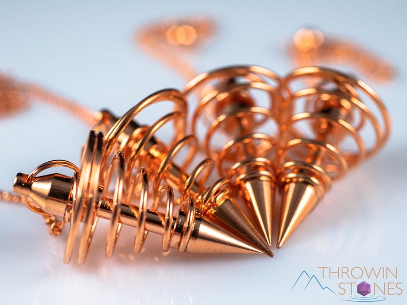 These copper pendulums are wire spirals with a pointed tip, with a copper chain and bead.