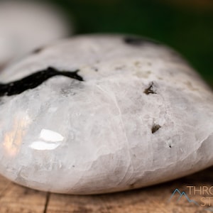 Genuine Moonstone heart shaped crystal. This beautifully hand carved, puffy, palm stone heart, is white with specks of black and rainbow flash. Each crystal heart is unique, and has its own color, shape, and pattern. This listing has variations.