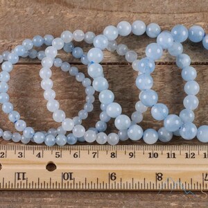 Handcrafted Aquamarine round beaded bracelet. These polished, blue beads are drilled and strung on elastic cord. Each crystal bracelet is unique in shape, color, and pattern and has a wrist circumference of about 6 to 7 inches. Listing has variations