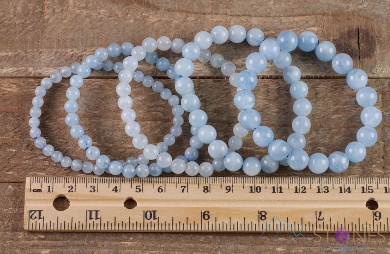 Handcrafted Aquamarine round beaded bracelet. These polished, blue beads are drilled and strung on elastic cord. Each crystal bracelet is unique in shape, color, and pattern and has a wrist circumference of about 6 to 7 inches. Listing has variations