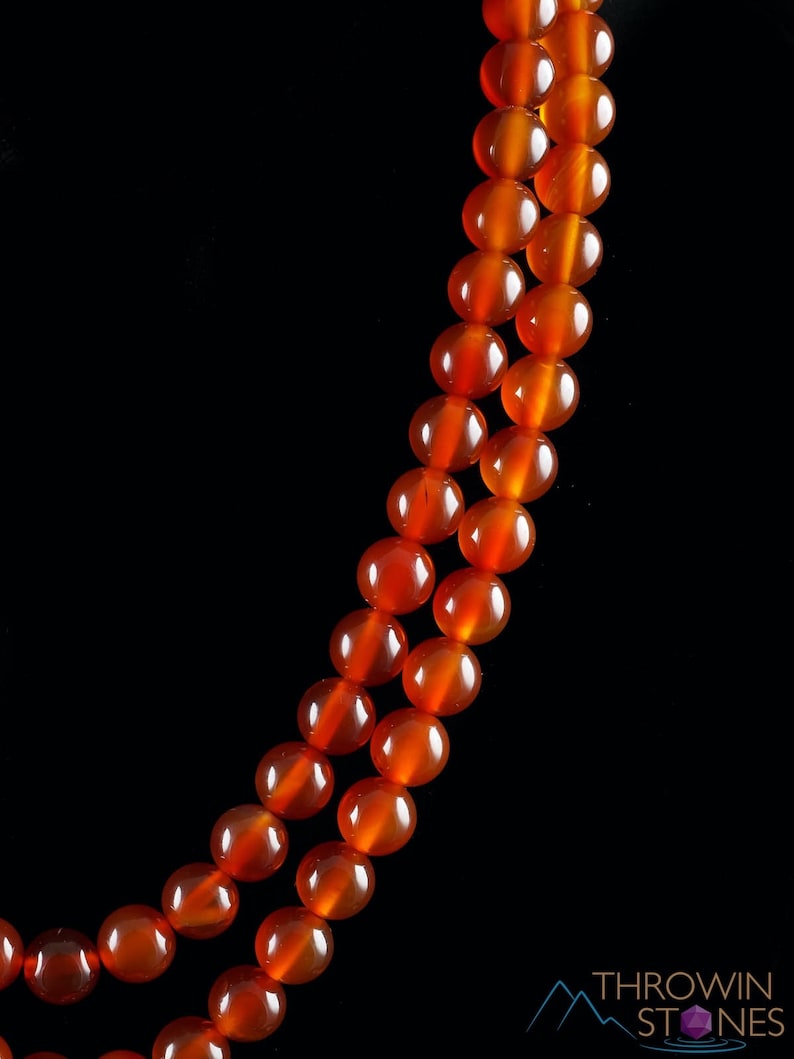 These red orange Carnelian necklaces have 108 sphere beads with a red tassel.  
Crystals are nature-made therefore each one is unique in appearance.