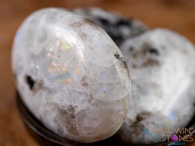 These Moonstone crystal carved polished palm stones range in a variety of handheld sizes.  Rainbow moonstone is white with black flecks and rainbow flashes.
Crystals are nature-made therefore each one is unique in appearance.
