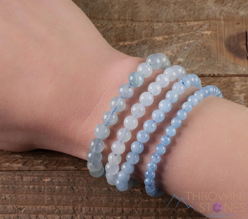 Handcrafted Aquamarine round beaded bracelet. These polished, blue beads are drilled and strung on elastic cord. Each crystal bracelet is unique in shape, color, and pattern and has a wrist circumference of about 6 to 7 inches. Listing has variations