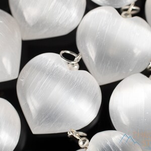 These chatoyant white Selenite crystal pendants are heart shaped, with a silver bail. 
Crystals are nature-made therefore each one is unique in appearance.