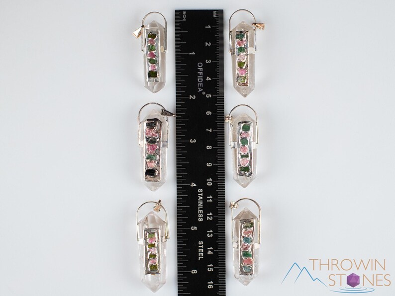 This crystal pendant features a clear Quartz gemstone, showcasing its transparent beauty and amplifying properties. Surrounding the Quartz are seven, green and pink Tourmaline gemstone accent crystals.
