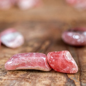 Rhodochrosite Crystal Chips. These stones are light pink to bright pink and often include a white banding. They are great for jewelry making and crystal decor. Each specimen is unique and varies in color, shape, and pattern. Listing has variations.