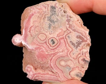 May include: Pink and gray banded agate with a swirling pattern. The agate has a smooth, polished surface.