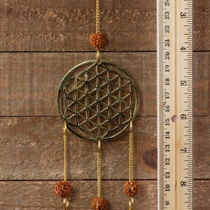 These are small brass wind chimes in the shape of a disc with the "flower of life" sacred geometry design, with bells and Rudraksha beads.