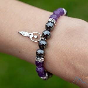 These purple Amethyst and grey Hematite crystal bracelets have round beads strung on elastic.  They feature a silver Goddess Charm.
Crystals are nature-made therefore each one is unique in appearance.