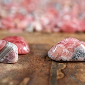 Rhodochrosite Crystal Chips. These stones are light pink to bright pink and often include a white banding. They are great for jewelry making and crystal decor. Each specimen is unique and varies in color, shape, and pattern. Listing has variations.