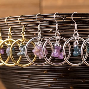 May include: A set of eight dangle earrings with silver and gold hoops. Each earring features a different coloured gemstone cluster.
