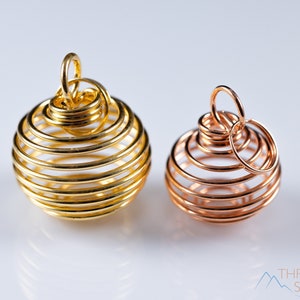 Puede incluir: Dos jaulas envueltas en alambre, una dorada y otra de cobre, para guardar cristales u otros objetos pequeños.