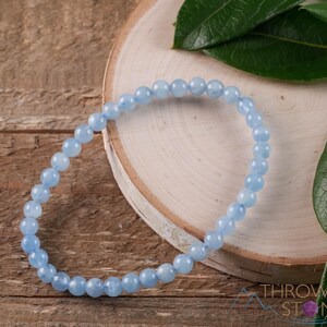 Handcrafted Aquamarine round beaded bracelet. These polished, blue beads are drilled and strung on elastic cord. Each crystal bracelet is unique in shape, color, and pattern and has a wrist circumference of about 6 to 7 inches. Listing has variations