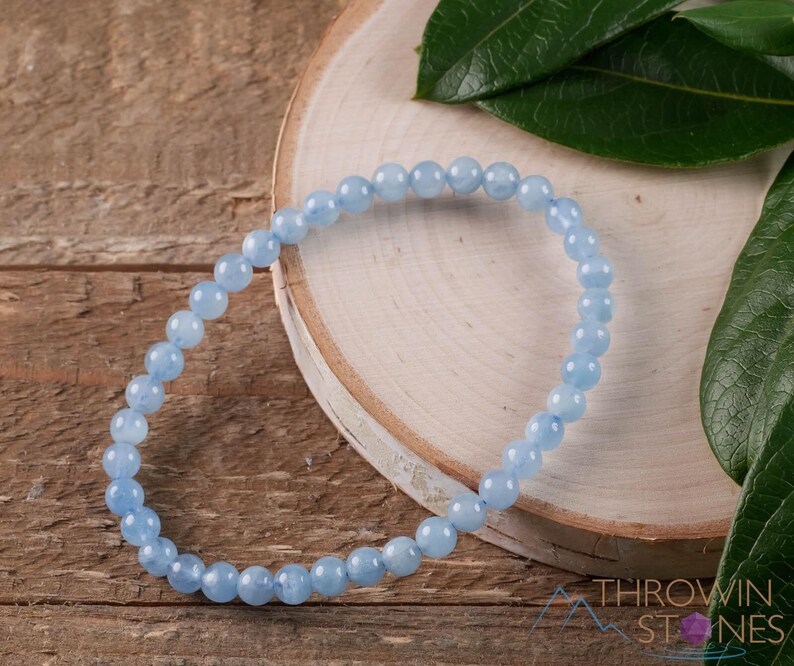 Handcrafted Aquamarine round beaded bracelet. These polished, blue beads are drilled and strung on elastic cord. Each crystal bracelet is unique in shape, color, and pattern and has a wrist circumference of about 6 to 7 inches. Listing has variations