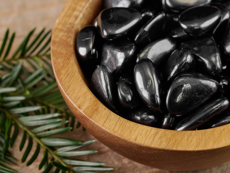 Hematite Tumbled Gemstones. These ethically sourced, semi precious, crystals are black with a polished finish. You will receive 5 stones that are 1.7 to 2.4 centimeters in length and weigh 25 to 35 grams total. Each stone is unique in shape and color