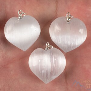 These chatoyant white Selenite crystal pendants are heart shaped, with a silver bail. 
Crystals are nature-made therefore each one is unique in appearance.