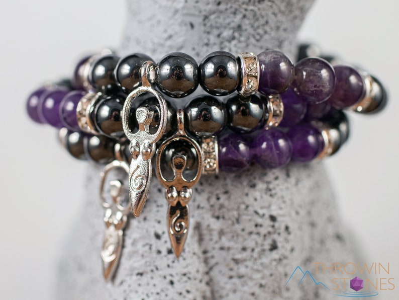 These purple Amethyst and grey Hematite crystal bracelets have round beads strung on elastic.  They feature a silver Goddess Charm.
Crystals are nature-made therefore each one is unique in appearance.