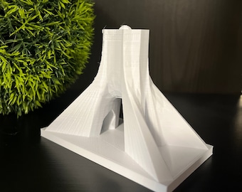 May include: A white 3D printed model of the Azadi Tower in Tehran, Iran. The model is detailed and shows the tower's unique architectural features.