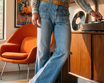 May include: A long-sleeve button-down shirt with a multi-coloured chevron pattern, light blue denim jeans with front patch pockets, a tan leather belt with a gold buckle, and tan leather boots with a stacked heel.