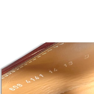 May include: The interior of a shoe featuring a tan leather lining with visible stitching along the top edge. Stamped in white text on the inner side are the numbers 608 4141 14 13 and the letter D, indicating specific product identification.