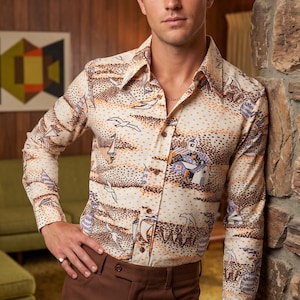 May include: A long-sleeve button-down shirt featuring a cream base with a repeating print of sailboats, birds, and small houses in shades of brown, orange, and blue. The shirt has a pointed collar, brown buttons, and is paired with solid brown trousers.