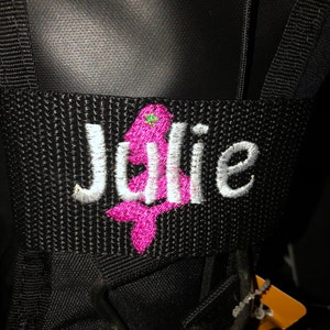 May include: Black golf bag with a white embroidered name "Julie" and a pink embroidered Christmas tree.