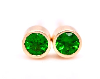 May include: A pair of gold stud earrings with green gemstones.