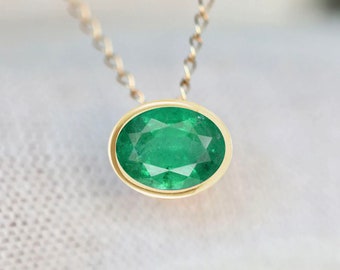 May include: A gold chain necklace with a green oval emerald gemstone pendant.