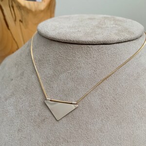 May include: A gold chain necklace with a silver triangle pendant.