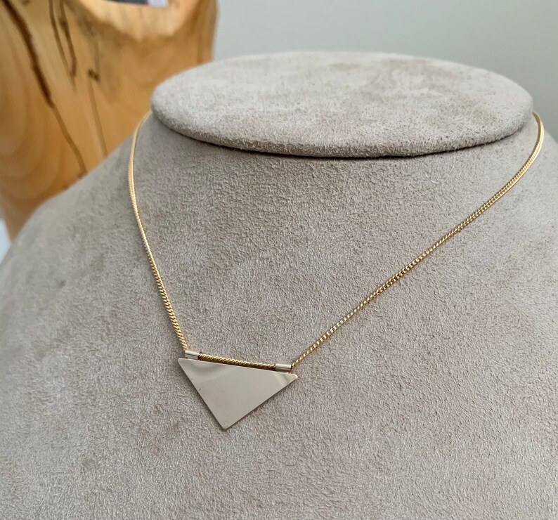 May include: A gold chain necklace with a silver triangle pendant.