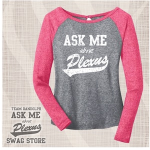 Può includere: Una maglietta a maniche lunghe rosa e grigia con una grafica bianca in stile baseball che dice "Ask Me about Plexus". La maglietta ha uno schema di colori rosa e grigio e un design a maniche raglan.