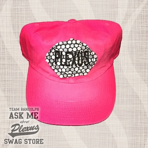 May include: Pink baseball cap with a black and white logo that says "Plexus" on it. The cap also has the text "TEAM RANDOLPH ASK ME about Plexus SWAG STORE" on it.