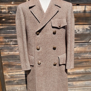 May include: A brown double-breasted coat with a textured weave. The coat has a notched lapel, two rows of buttons, and two front pockets. The coat is displayed on a mannequin.