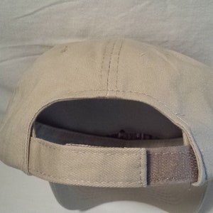 May include: A beige baseball cap with a brown adjustable strap in the back.