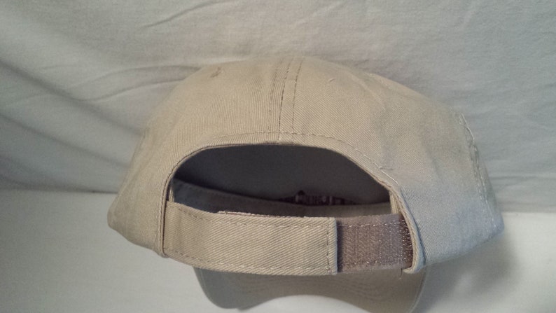 May include: A beige baseball cap with a brown adjustable strap in the back.