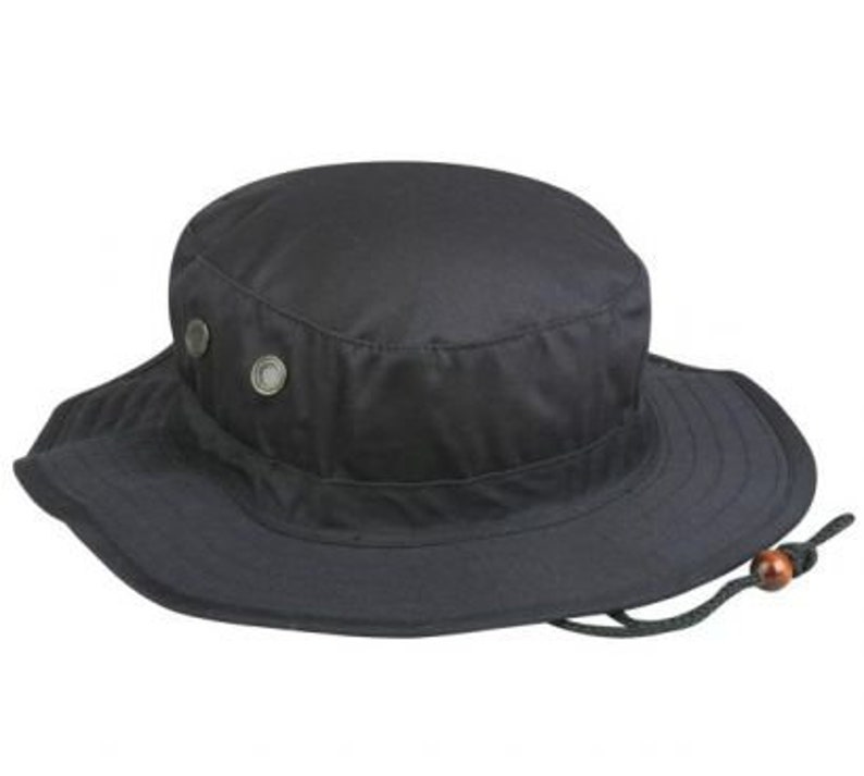 May include: A black, wide-brimmed hat with a round crown and a chin strap. The hat features two metal rivets on the crown and a drawstring with a wooden bead. The brim is slightly sloped.