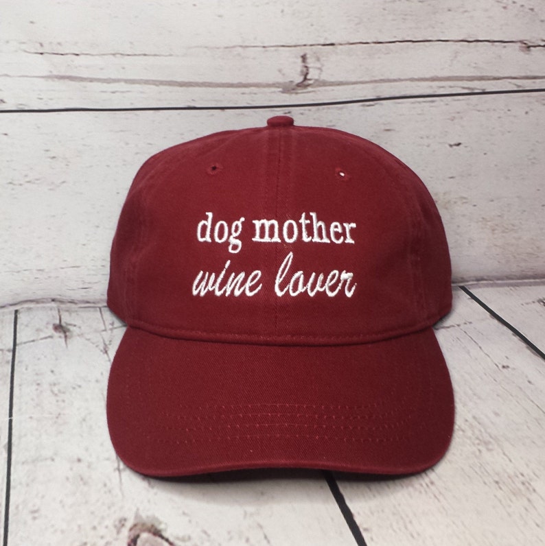 May include: A red baseball cap with white embroidery that reads "dog mother wine lover".