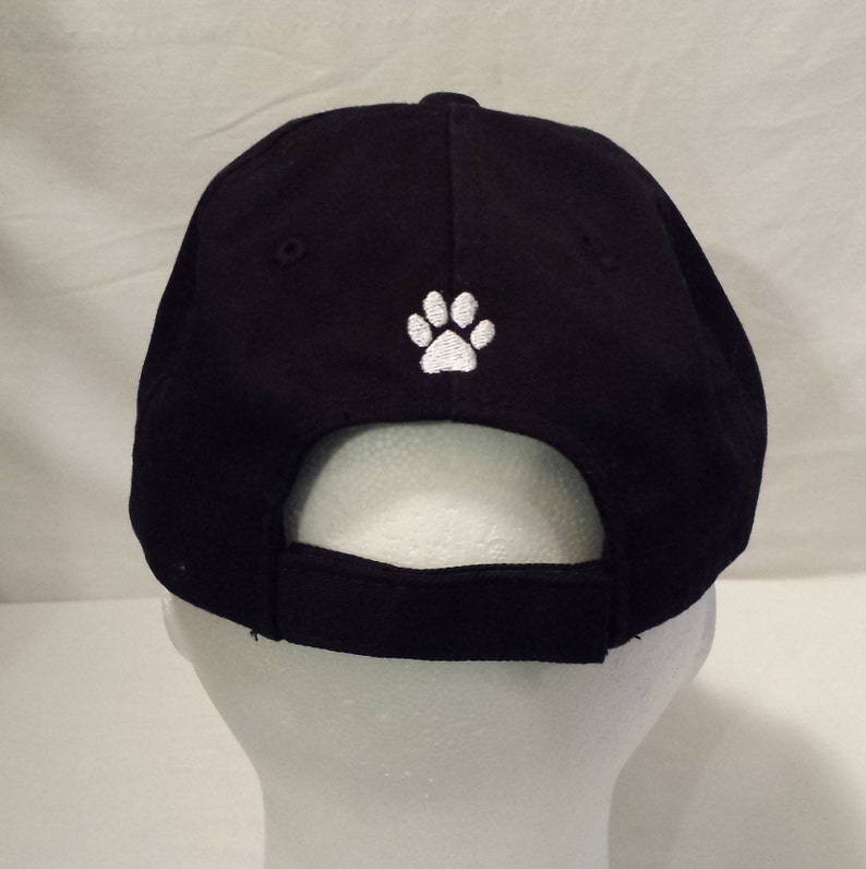 May include: Black baseball cap with a white paw print embroidered on the back.