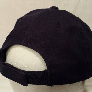 May include: A navy blue baseball cap with a curved brim and adjustable strap. The cap is made of a durable fabric and features a classic six-panel design. The adjustable strap allows for a comfortable fit.