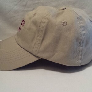 May include: A beige baseball cap with a red embroidered logo that says "Church 83".